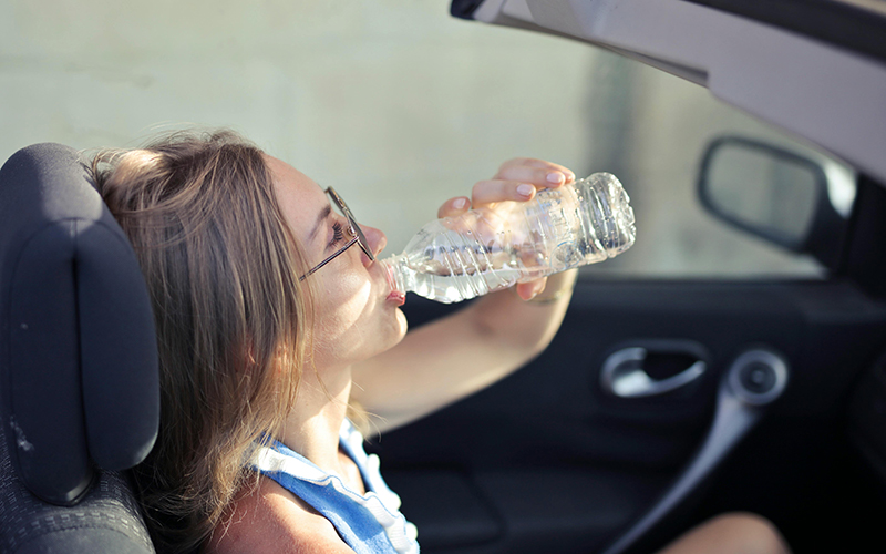 Frau trinkt Wasser im Auto